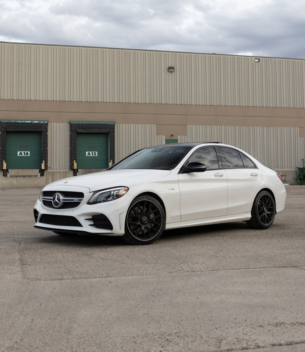 White Mercedes Benz sedan with black wheels showcasing a luxury style and automotive wrap, vehicle is detailed and cleaned