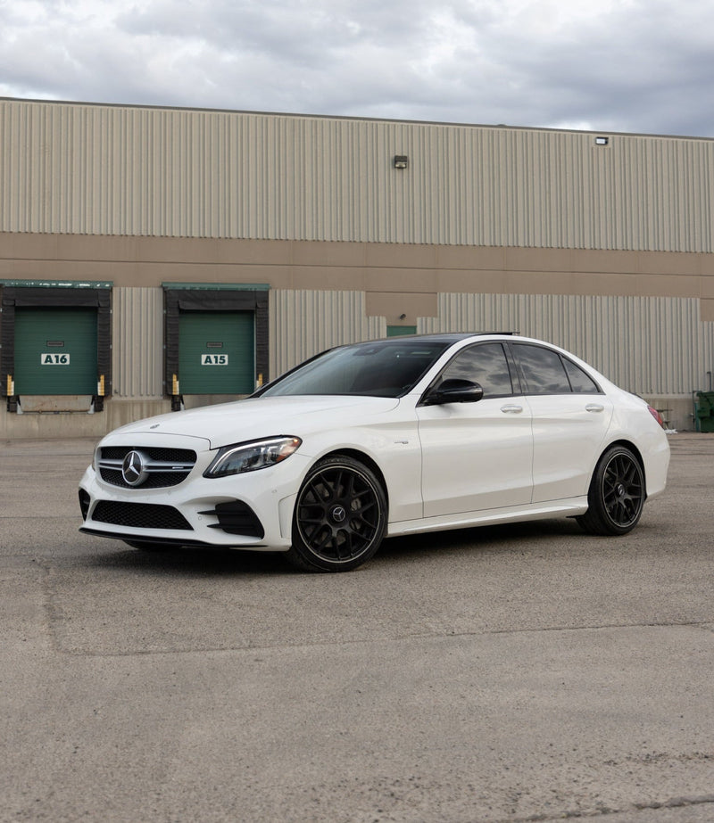 White Mercedes Benz sedan with black wheels showcasing a luxury style and automotive wrap, vehicle is detailed and cleaned