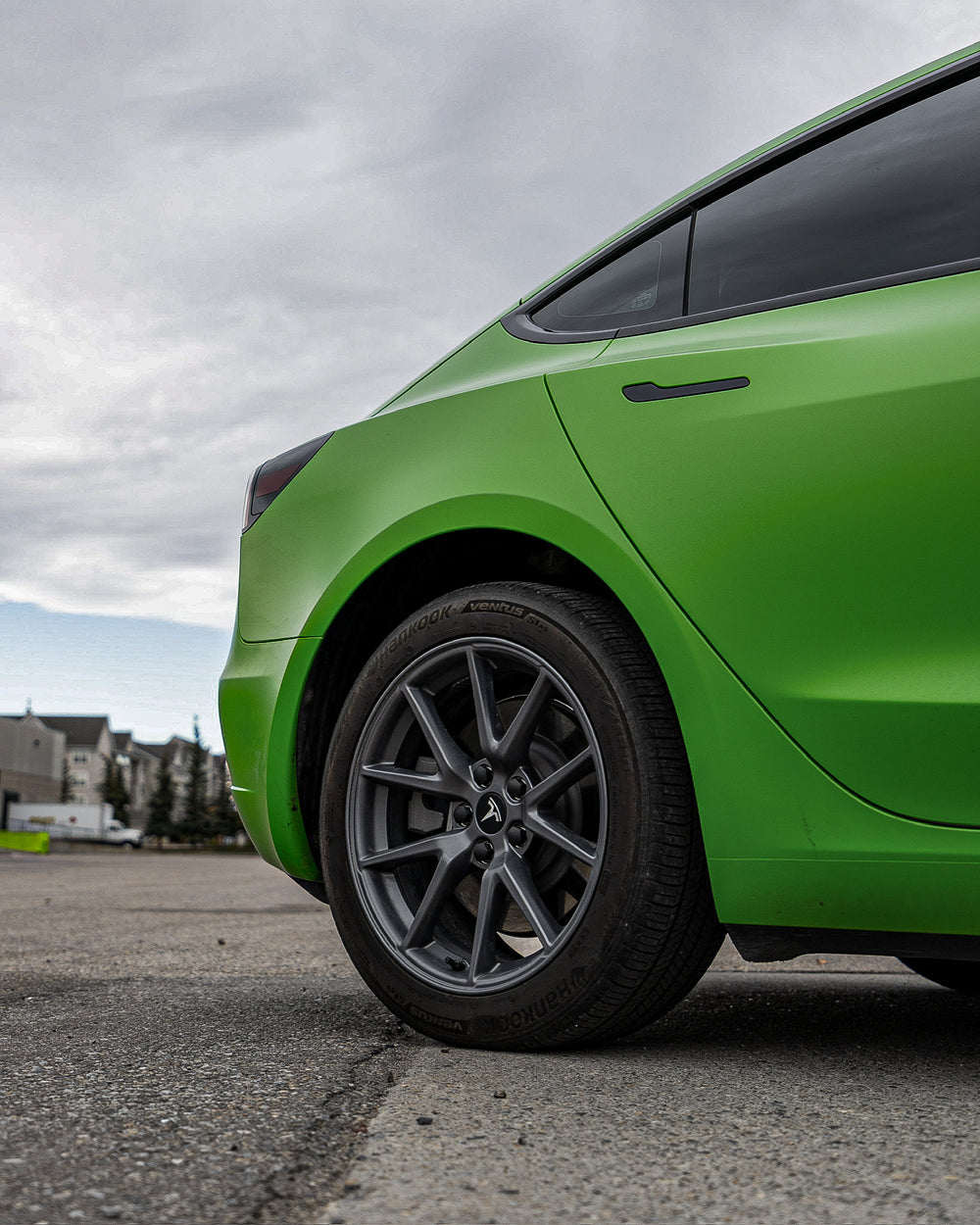 Bright green Tesla Model 3 wrapped in 3M vehicle wrapping vinyl, with custom wheels featuring premium stealth paint protection film on top