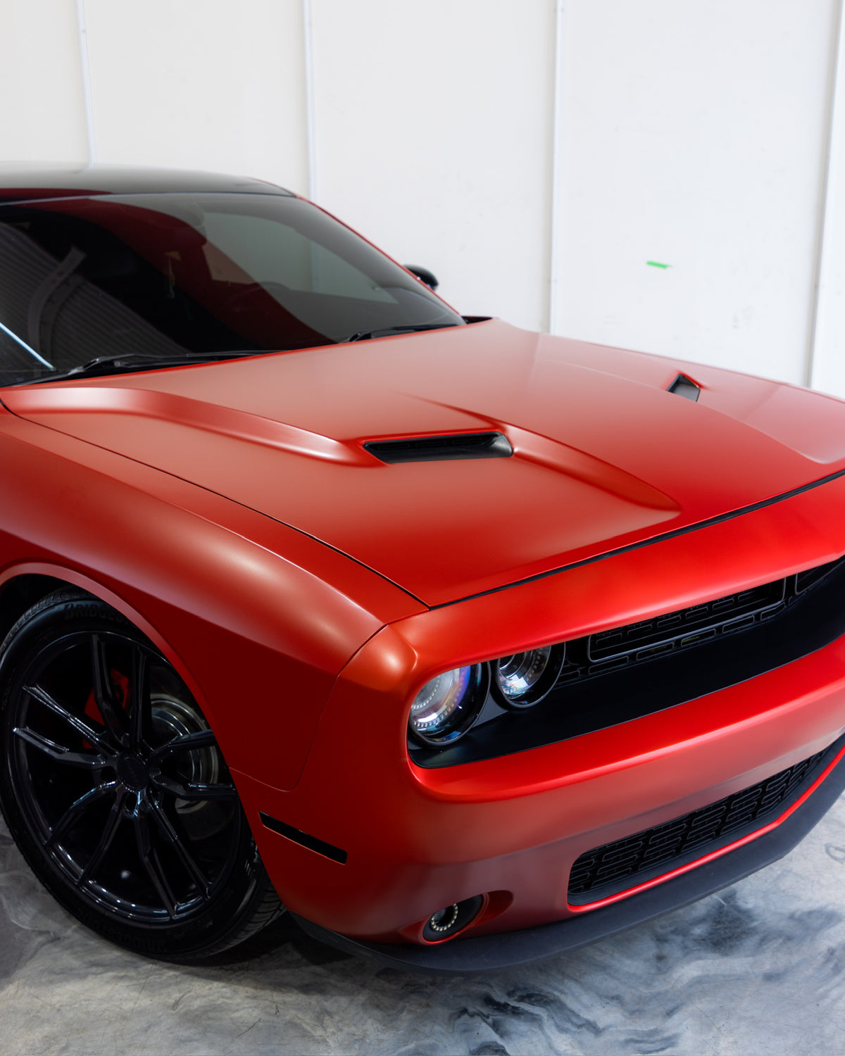 Red sports car with black powdercoated  rims on a white background showcasing a bright red vinyl wrap