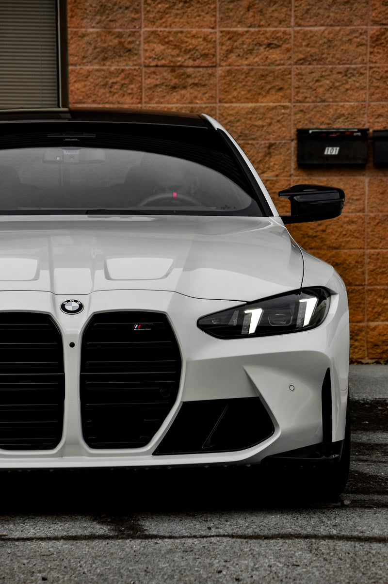 White BMW car parked against a brown brick wall
