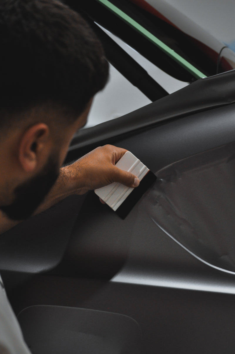 High quality installer laying down some coloured ppf on the rear quarter panel of a vehicle
