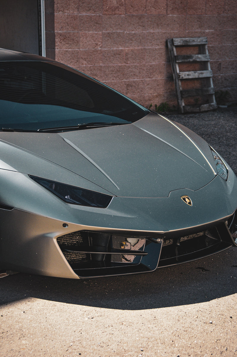 Front view of a Lamborghini sports car parked against a brick wall.