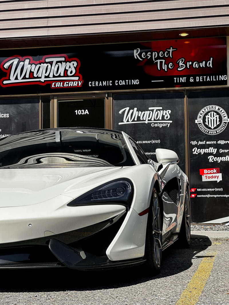 White McLaren sports car in front of the shop with a full ceramic tint project completed